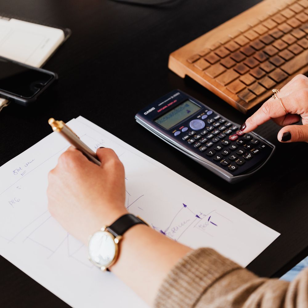 Mâini pregătind calcule și documente financiare la birou